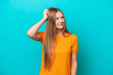 Genç Rus kadın mavi arka planda izole edildi. Kafası kaşınırken şüpheleri vardı.