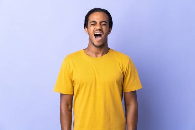 Örgülü genç Afrikalı Amerikalı adam mor arka planda izole edilmiş ve ağzı açık bir şekilde öne doğru bağırıyor.