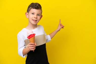 Sarı arka planda izole edilmiş kornet dondurması olan beyaz bir çocuk.