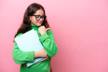 Pembe arka planda izole edilmiş küçük kız bir ürünü sunmak için kenarı işaret ediyor.