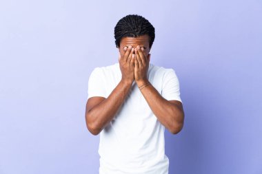Örgülü genç Afrikalı Amerikalı adam mor arka planda izole edilmiş, yorgun ve hasta bir ifadeyle.