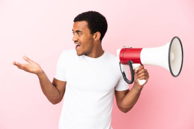 Soyutlanmış pembe arka planda Afro-Amerikalı yakışıklı bir adam elinde bir megafon ve şaşırtıcı bir yüz ifadesiyle
