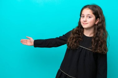 Mavi arka planda izole edilmiş küçük bir kız. Davet etmek için ellerini yana uzatıyor.