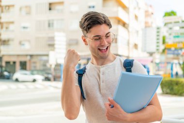 Genç yakışıklı öğrenci dışarıda zaferi kutluyor.