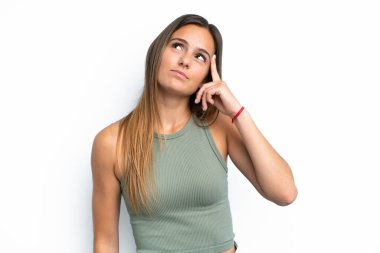 Beyaz arka planda soyutlanmış genç beyaz bir kadın deliliğin jestini yapıyor. Parmağını kafaya koyuyor.