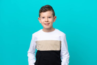 Küçük çocuk mavi arka planda yalnız gülüyor.