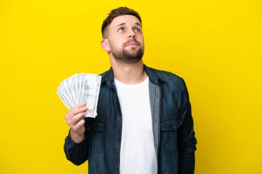 Kafkasyalı genç bir adam çok para alıyor. Sarı arka planda izole edilmiş ve araştırılıyor.