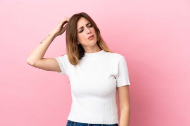 Kafkasyalı kadın pembe arka planda izole edilmiş. Kafası kaşınırken şüpheleri var.