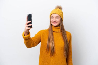 Beyaz arka planda izole edilmiş, kışlık ceket giyen beyaz bir kadın selfie çekiyor.