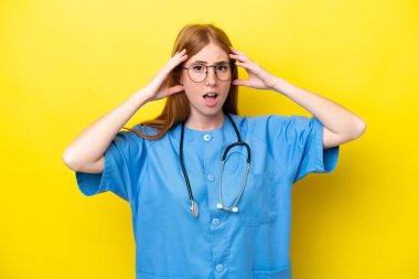 Sarı arka planda, sürpriz bir ifadeyle izole edilmiş genç kızıl saçlı hemşire kadın.