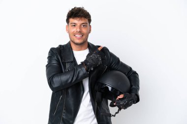 Beyaz arka planda izole edilmiş motosiklet kasklı beyaz bir adam bir ürünü sunmak için kenarı işaret ediyor.