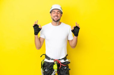 Zen pozisyonunda sarı arka planda izole edilmiş genç kaya tırmanıcısı.