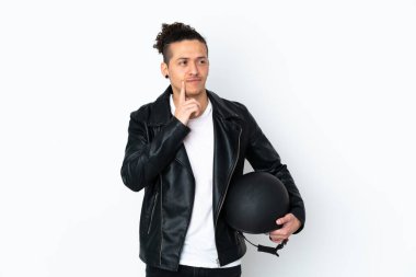Beyaz arka plan üzerinde motosiklet kaskı olan beyaz bir adam bir fikir düşünüyor.