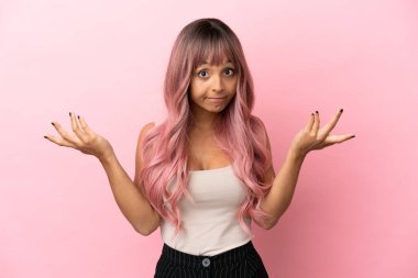 Pembe saçlı melez bir kadın pembe arka planda kuşkulu hareketler yapıyor.