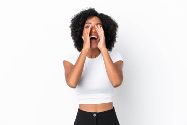 Genç Afrikalı Amerikalı kadın beyaz arka planda izole edilmiş bağırıyor ve bir şey duyuruyor.