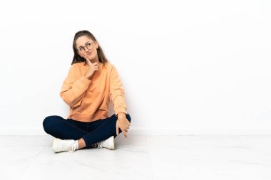 Genç bir kadın yerde oturuyor, kafasında şüpheler var.