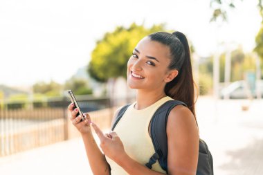 Açık havada cep telefonu kullanan genç ve güzel bir kadın.
