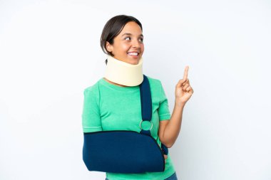 Young hispanic woman wearing a neck brace and sling isolated on white background pointing up a great idea