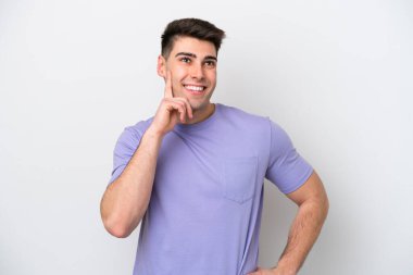 Beyaz arka planda izole edilmiş genç beyaz adam yukarı bakarken bir fikir düşünüyor.