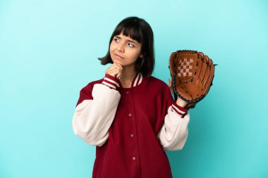 Beyzbol eldivenli, genç, melez bir kadın. Mavi arka planda izole edilmiş ve araştırılıyor.
