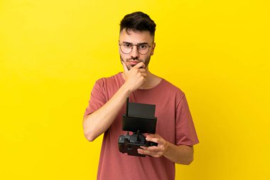 Elinde uzaktan kumanda tutan adam sarı arka planda izole edilmiş.