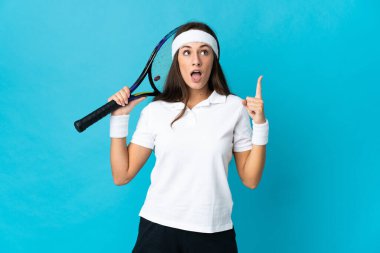 Tecrit edilmiş mavi arka planda genç İspanyol kadın tenis oynuyor ve...