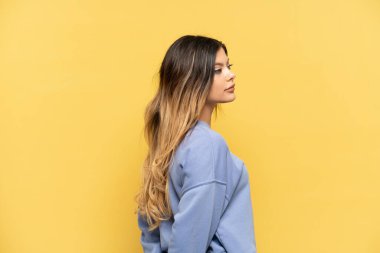 Genç Rus kız sarı arka planda izole edilmiş ve arkasına bakıyor.