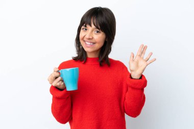 Beyaz arka planda izole edilmiş bir fincan kahve tutan beyaz bir kadın mutlu bir ifadeyle selamlıyor.