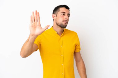 Beyaz arka planda izole edilmiş yakışıklı beyaz adam dur hareketi yapıyor ve hayal kırıklığına uğruyor.