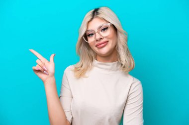 Mavi arka planda gözlüklü ve işaret eden genç Rus kadın.