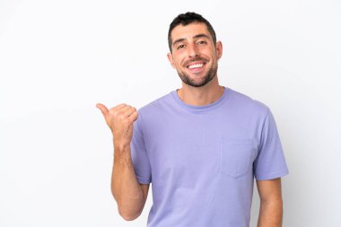 Beyaz arka planda izole edilmiş yakışıklı beyaz adam bir ürün sunmak için kenarı işaret ediyor.