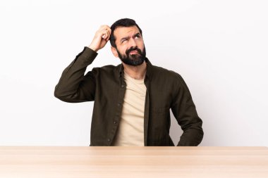 Masada sakallı, kafatası kaşınırken şüpheleri olan beyaz bir adam..