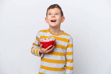 Beyaz arka planda izole edilmiş mısır gevreği kasesi tutan beyaz çocuk gülüyor.