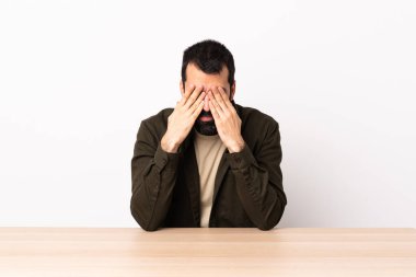 Masada sakallı, gözleri elle kaplanmış beyaz bir adam..