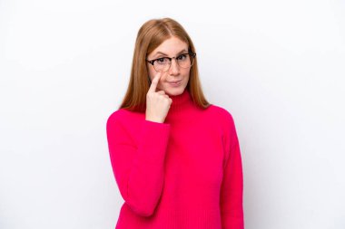 Beyaz arka planda izole edilmiş genç kızıl saçlı kadın bir şey gösteriyor.