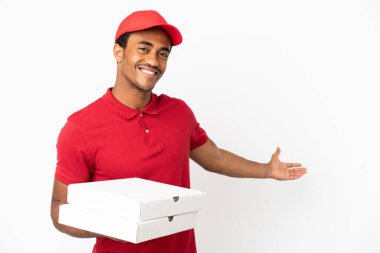 Afro-Amerikalı pizza teslimatçısı izole edilmiş beyaz duvardan pizza kutularını alıyor. Gelmesi için ellerini yana uzatıyor.