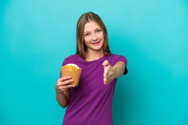 Mavi arka planda izole edilmiş patates kızartması yakalayan genç Rus kadın iyi bir anlaşma için el sıkışıyor.