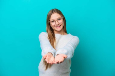 Mavi arka planda izole edilmiş genç bir Rus kadın bir ilan vermek için avucunun içinde hayali bir fotokopi makinesi tutuyor.