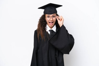 Üniversite mezunu genç bir Arap kadın beyaz arka planda gözlüklü ve şaşırmış.