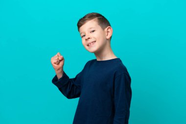 Küçük çocuk mavi arka planda izole bir şekilde zaferi kutluyor.