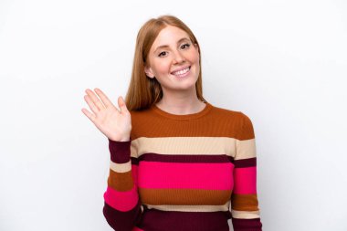 Genç kızıl saçlı kadın, beyaz arka planda soyutlanmış, mutlu bir ifadeyle selamlıyor.