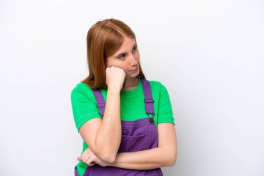 Genç kızıl saçlı kadın beyaz arka planda soyutlanmış, yorgun ve sıkılmış bir ifadeyle.