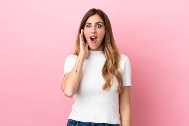 Beyaz kadın pembe arka planda izole edilmiş, şaşırmış ve şok olmuş bir yüz ifadesi var.