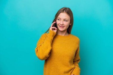 Mavi arka planda izole edilmiş genç bir Rus kadın cep telefonuyla biriyle sohbet ediyor.