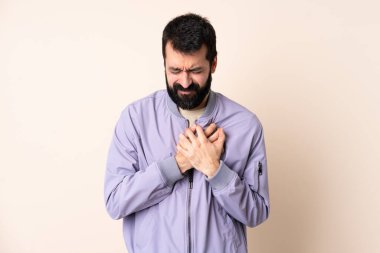 Sakallı, soyutlanmış arka planda ceket giyen beyaz bir adam. Kalbinde bir ağrı var.