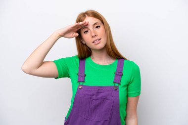 Genç kızıl saçlı kadın, beyaz arka planda soyutlanmış, mutlu bir ifadeyle selamlıyor.