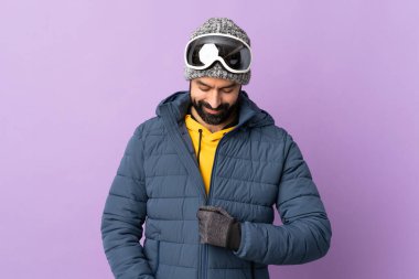 İzole edilmiş mor arka planda snowboard gözlüklü kayakçı.