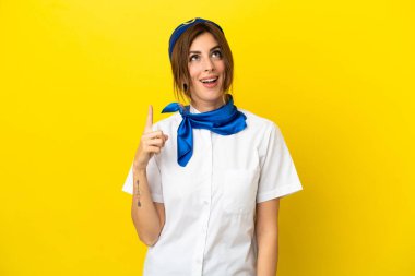 Uçak hostesi kadın sarı arka planda izole edilmiş yukarı bakıyor ve şaşırıyor.