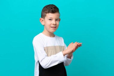Küçük çocuk mavi arka planda izole olmuş alkışlıyor.