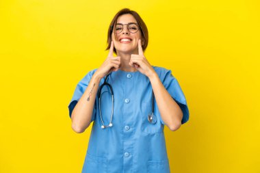 Doktor kadın, sarı arka planda izole edilmiş mutlu ve hoş bir ifadeyle gülümsüyor.